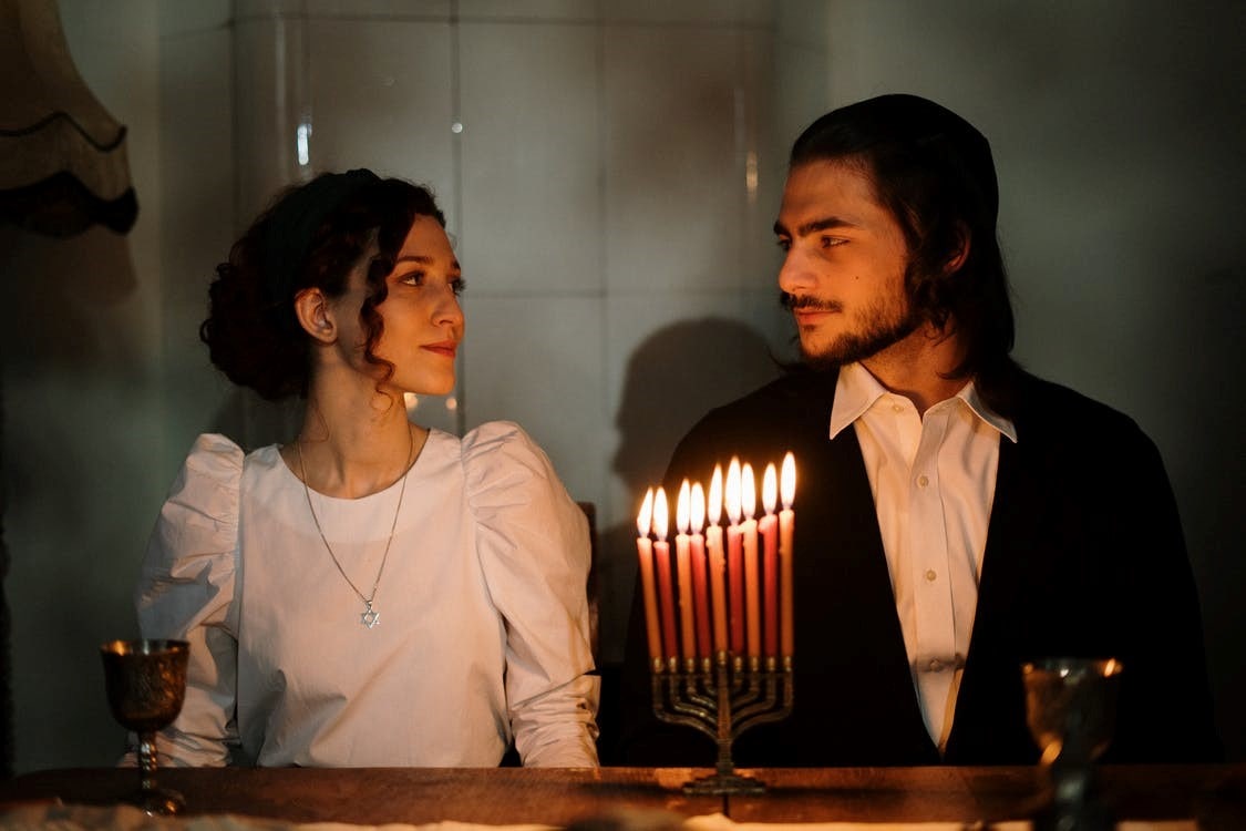 A couple looking at each other while sitting near a menorah