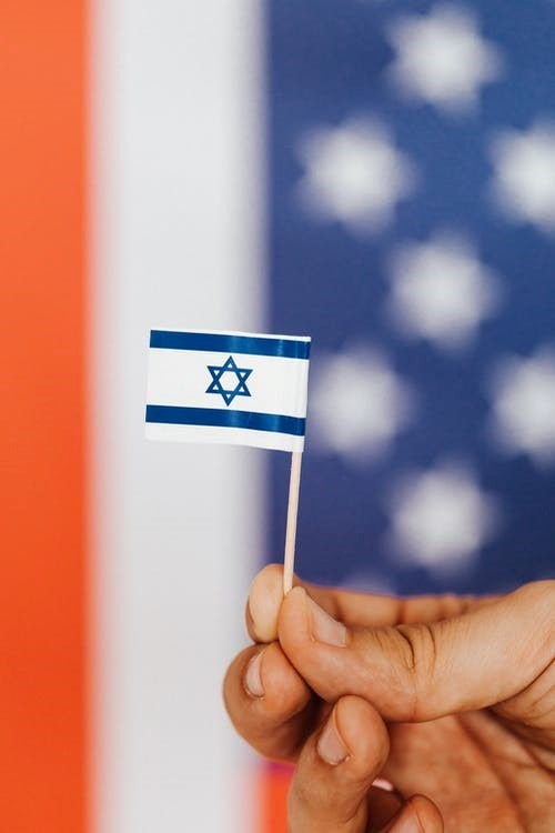 A person holding a miniature version of the Israel flag