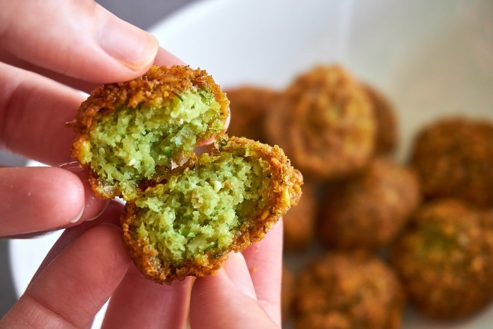 A person showing the inside of a fried falafel