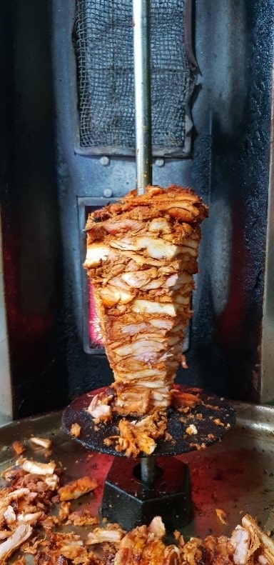 Chicken cooking on a shawarma burner