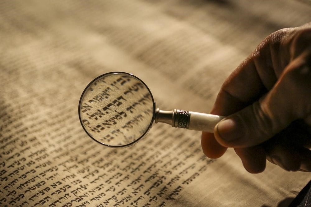 a person reading Hebrew through a magnifying glass