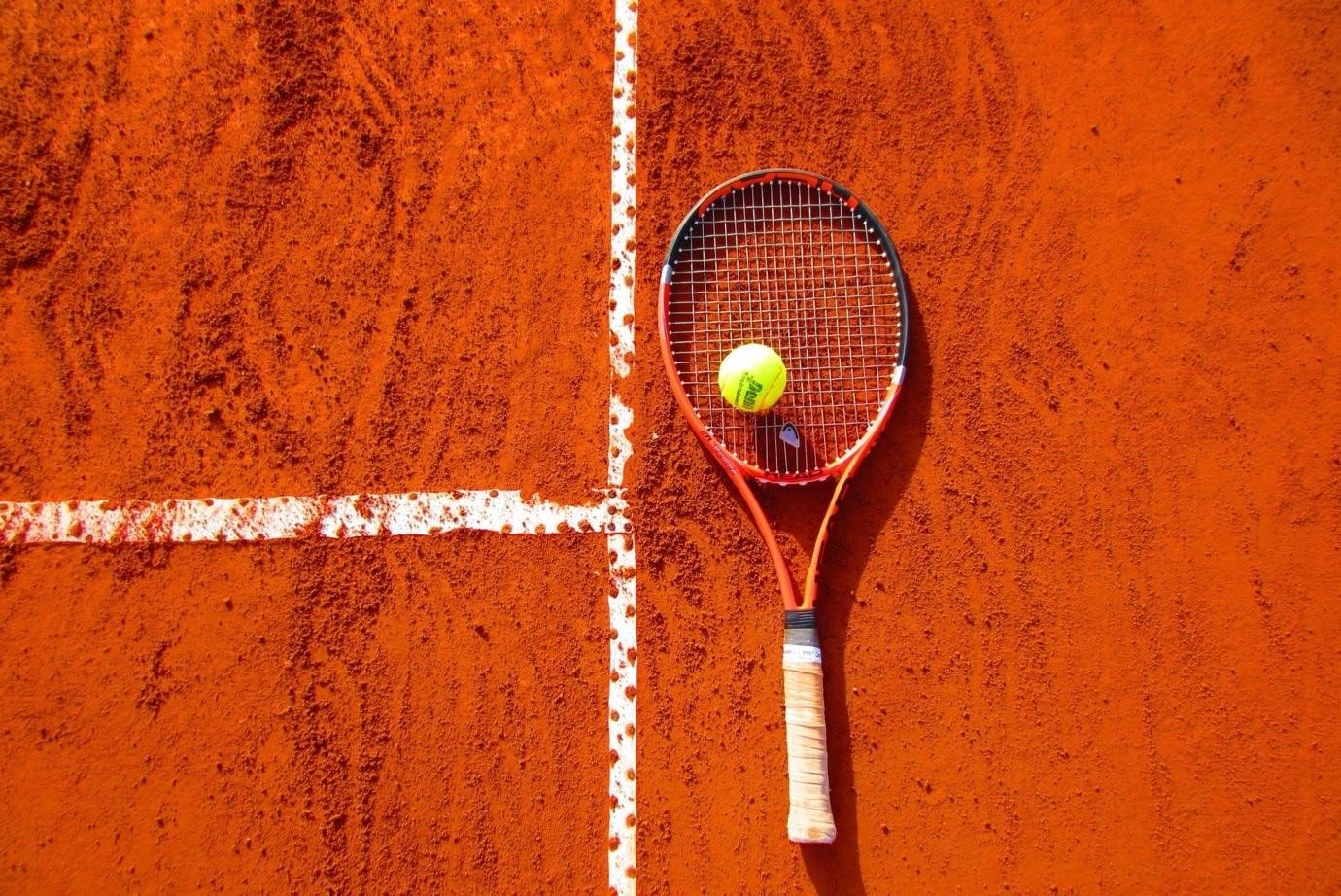 a tennis ball on a racquet on a clay court